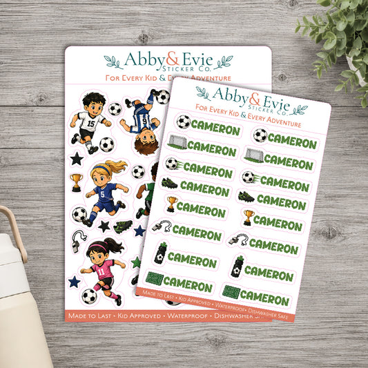 Two sticker sheets from Abby & Evie Sticker Co. featuring soccer-themed designs, displayed on a gray wood background with a small plant and part of a bag visible.