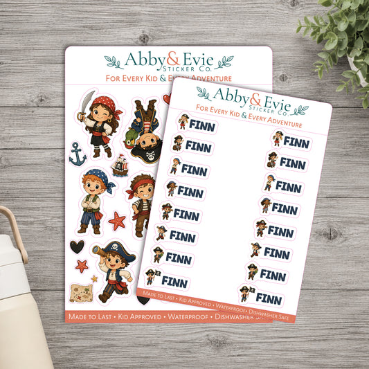 Two printable sticker sheets from Abby & Evie Sticker Co. featuring pirate-themed cartoon characters and repeated 'FINN' labels, arranged on a gray wood surface with a small plant and part of a bag visible at the edges.