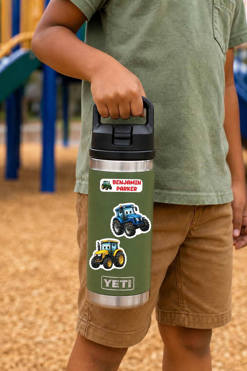 A child in a green shirt and tan shorts holds a green Yeti water bottle with tractor illustrations and 'Benjamin Parker' text at a playground.