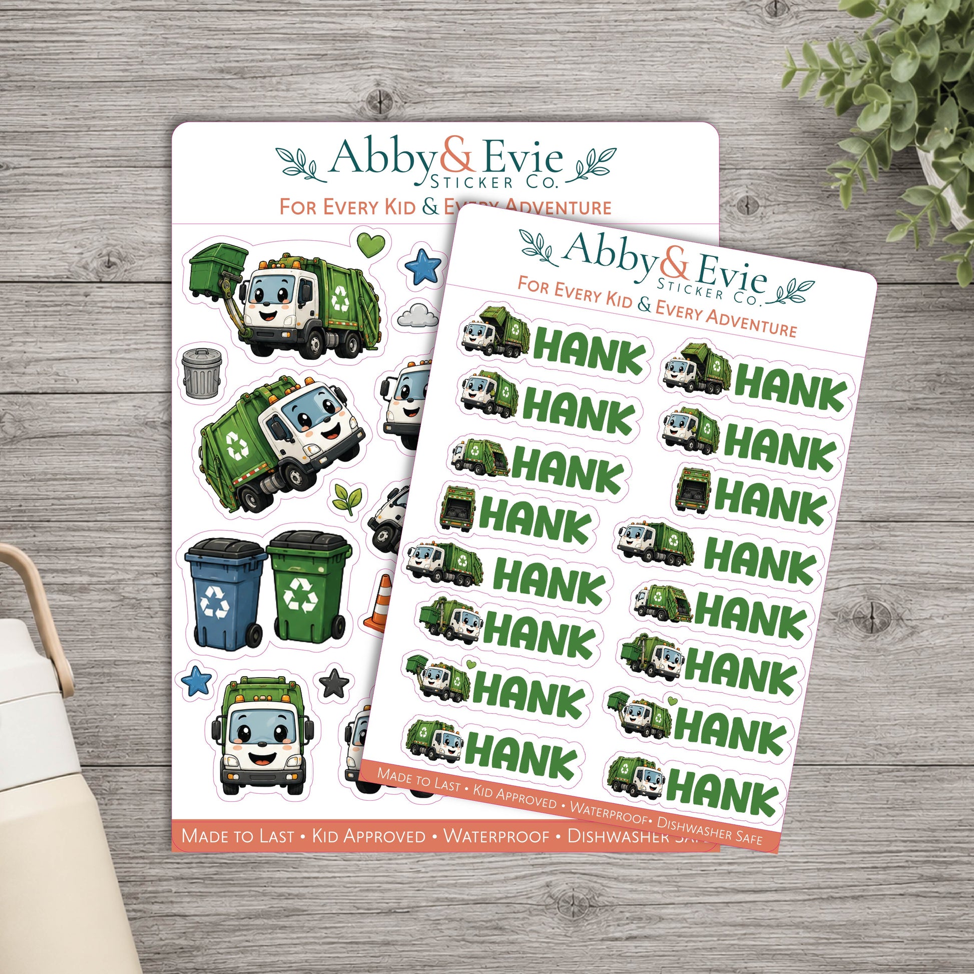 Two sticker sheets from Abby & Evie Sticker Co. featuring green and blue trash cans and a smiling garbage truck character, with the name HANK repeated across one sheet, displayed on a gray wood surface.