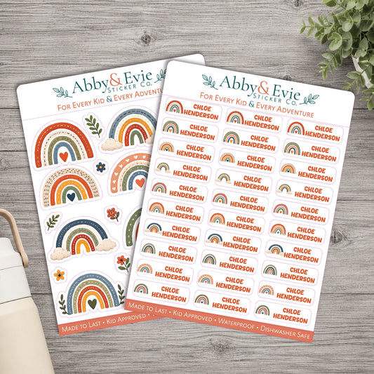 Two sticker sheets from Abby & Evie Sticker Co. featuring colorful rainbow designs and the name 'Chloe Henderson' repeated across the sheets, styled on a gray wood tabletop with a plant and notebook in the background.